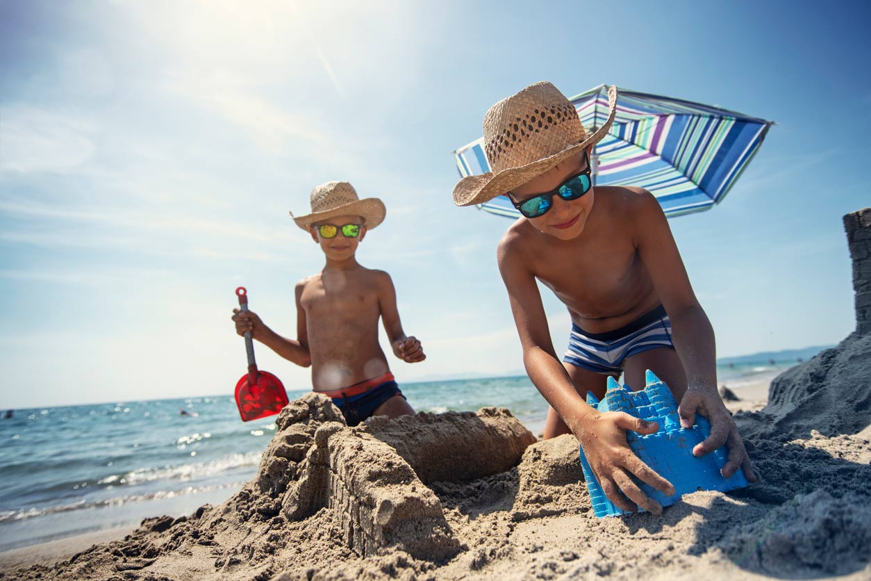 little boys building sandcastle on beach